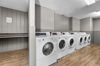 A row of white front load washing machines in a laundromat.